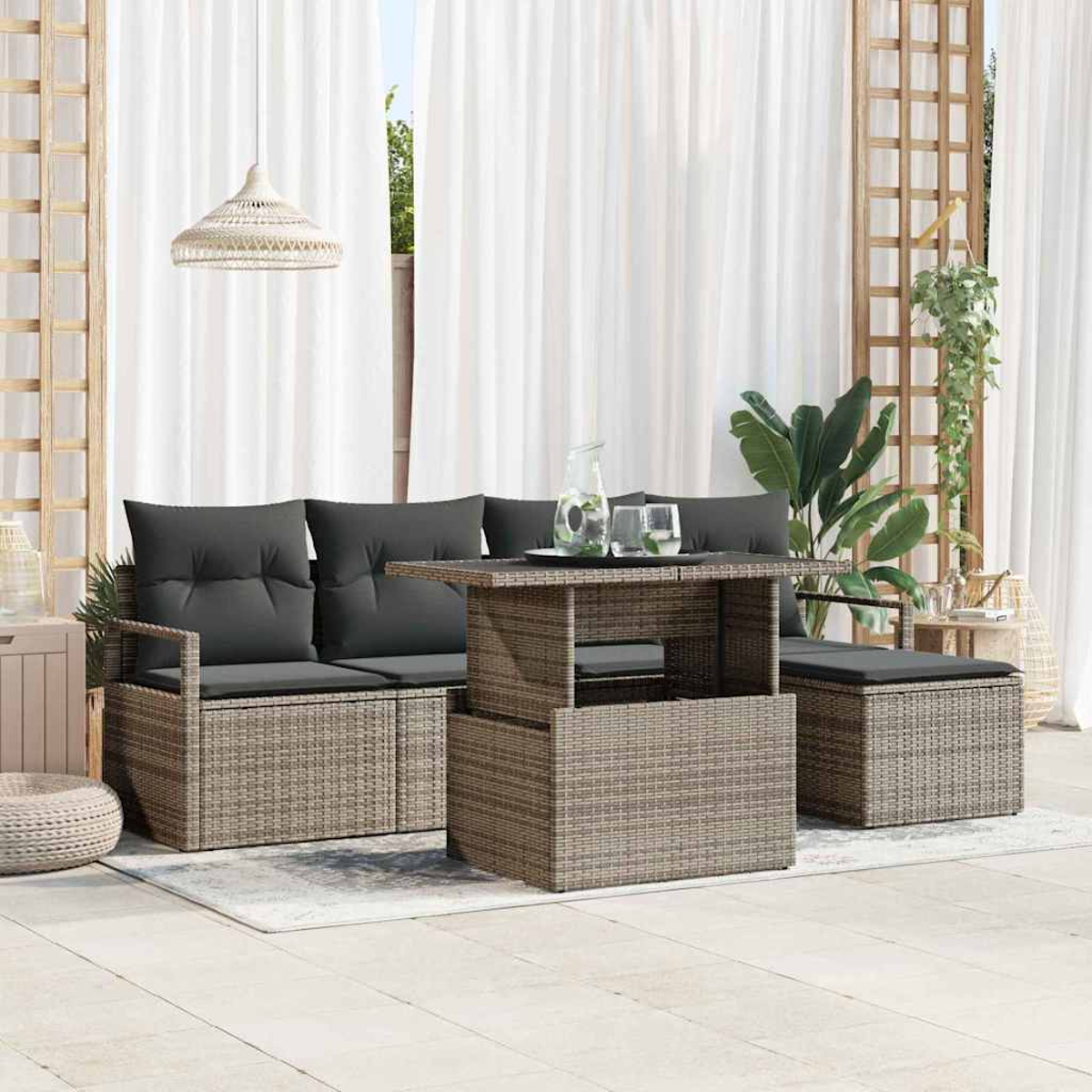Garten-Terrassenset mit grauen Kissen, einem Tisch mit Wassergläsern und weißen Vorhängen im Hintergrund.