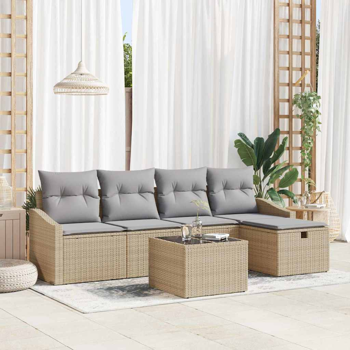 Outdoor-Sitzgruppe mit beigem Korbmöbelsofa, grauen Kissen und einem quadratischen Couchtisch. Weiße Vorhänge und Pflanzen im Hintergrund.