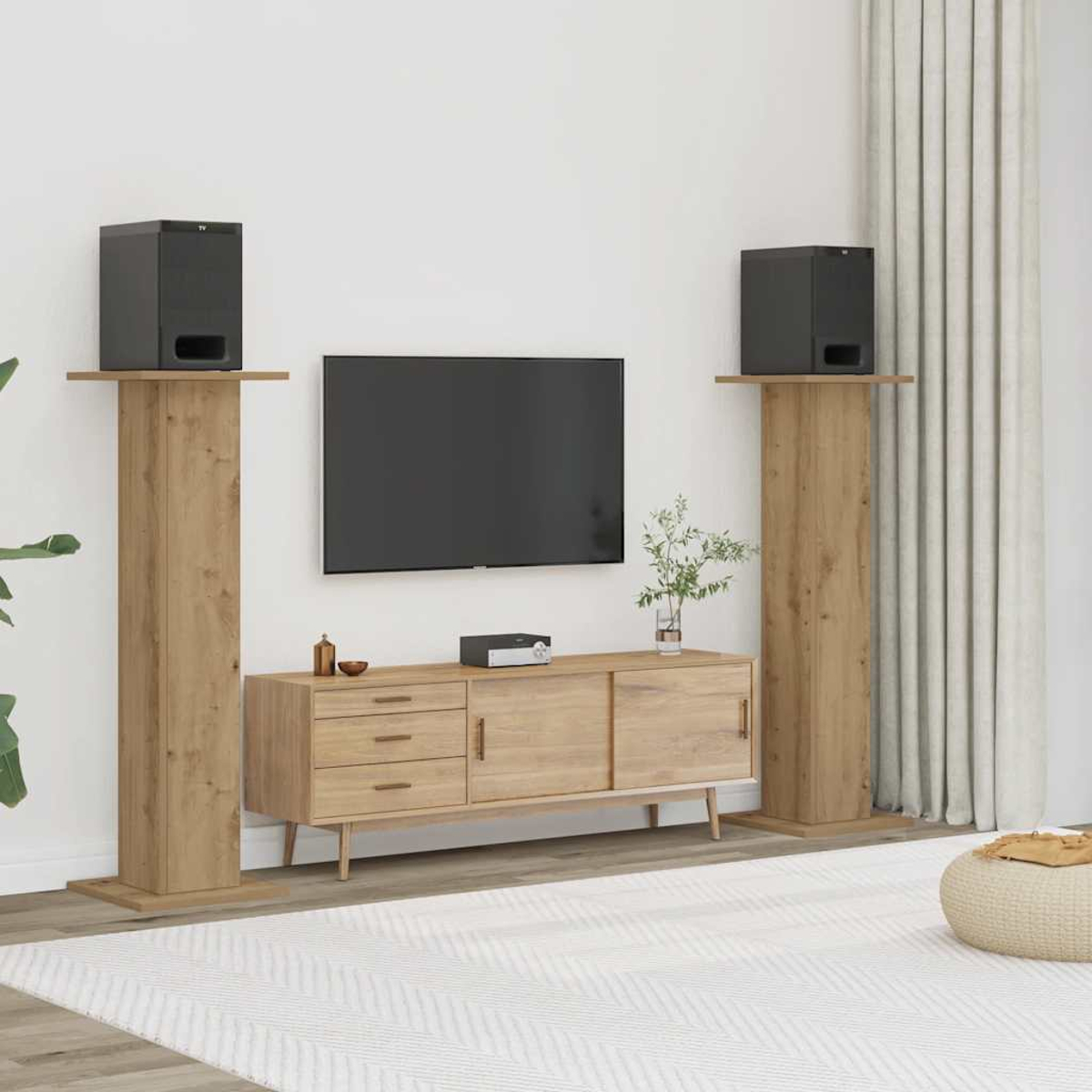 Wohnzimmer mit Fernseher, Lautsprechern auf Holzständern, Holzschrank, Teppich und Pouf. Vorhänge und eine Pflanze sind ebenfalls sichtbar.