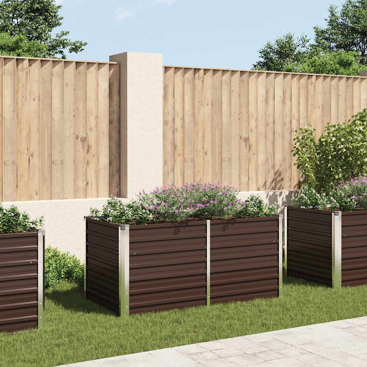 Drei braune Pflanzkästen mit Blumen stehen auf Gras. Ein Holzzaun und eine helle Wand sind im Hintergrund.