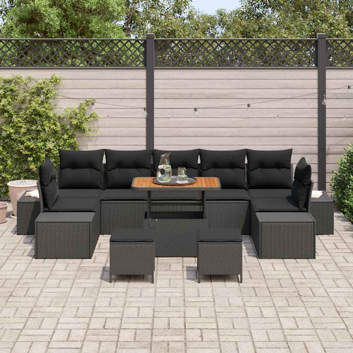 Garten-Set mit schwarzen Kissen und Holztisch. Hintergrund ist ein Holzzaun und Grün, was eine entspannende Szene schafft.