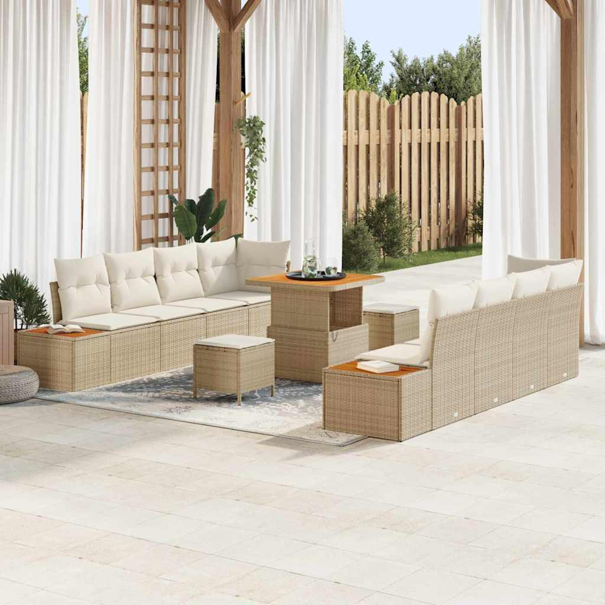 Outdoor-Sitzbereich mit Korbmöbeln, weißen Vorhängen und einem Holzzaun im Hintergrund. Beige Kissen und ein kleiner Tisch.