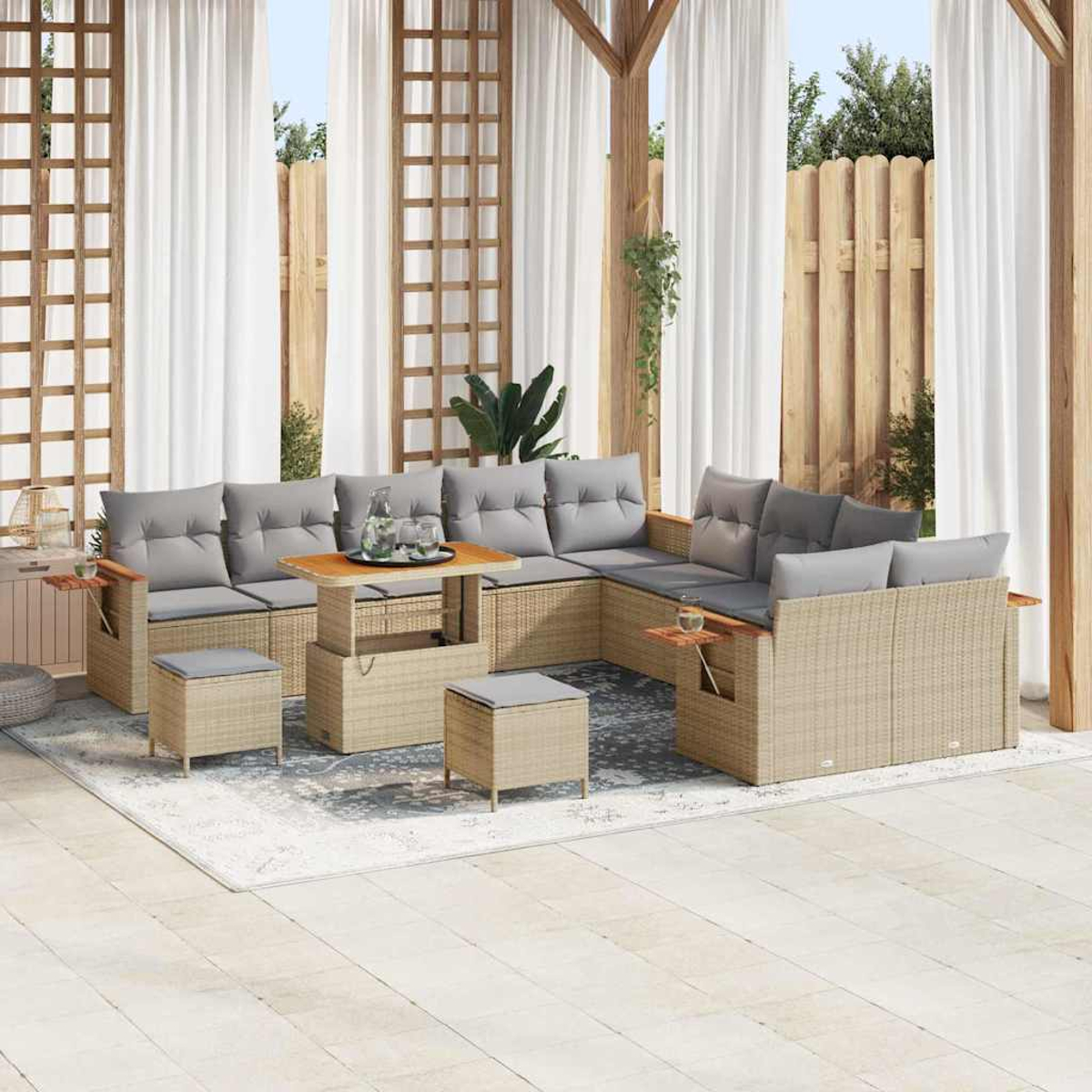 Set di sedute per esterni con cuscini grigi, un tavolo in legno e pouf. Tende bianche e una recinzione in legno completano il patio.