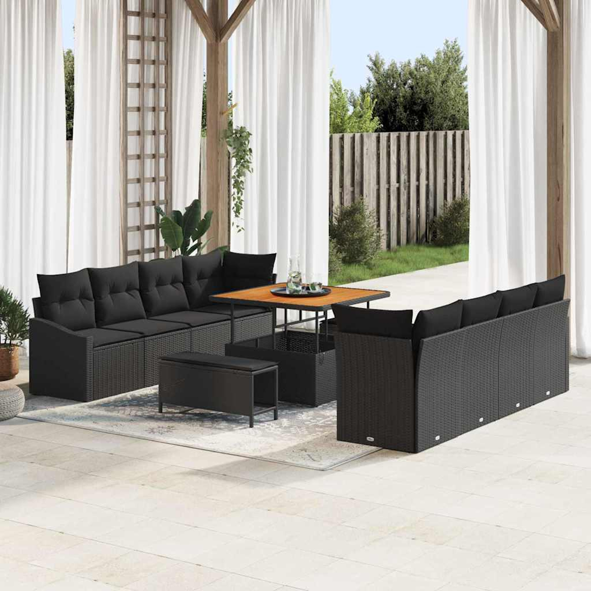 Outdoor-Terrassenset. Schwarze Korbsessel mit schwarzen Kissen, ein Holztisch und eine kleine Bank auf einem hellen Teppich.