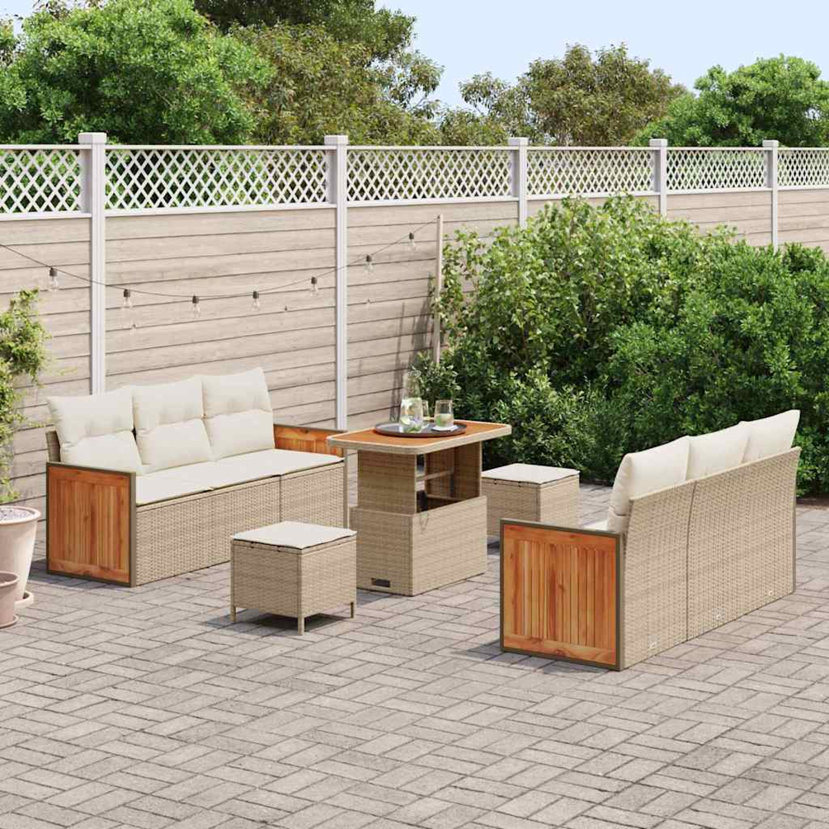 Garten-Terrassenset: zwei Sofas, zwei Ottomanen und ein Tisch auf einer Ziegelterrasse, mit weißem Zaun und Grün im Hintergrund.