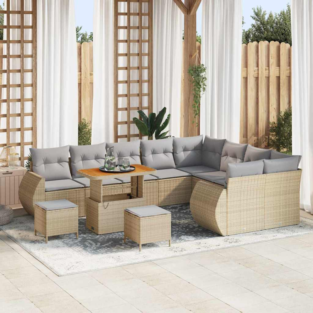 Outdoor-Ecksofa mit grauen Kissen, Holztisch und zwei Hockern. Weiße Vorhänge und Holzzaun im Hintergrund.