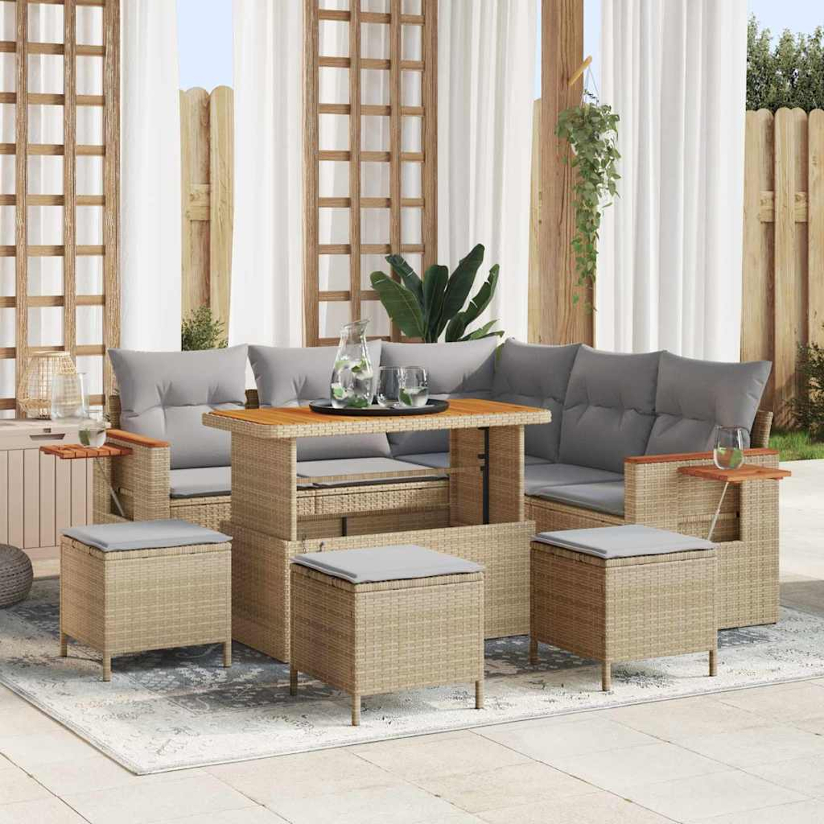 Gartenmöbel-Set aus Rattan. Graue Kissen, Holztisch, Hocker. Vorhänge und ein Holzgitter im Hintergrund.