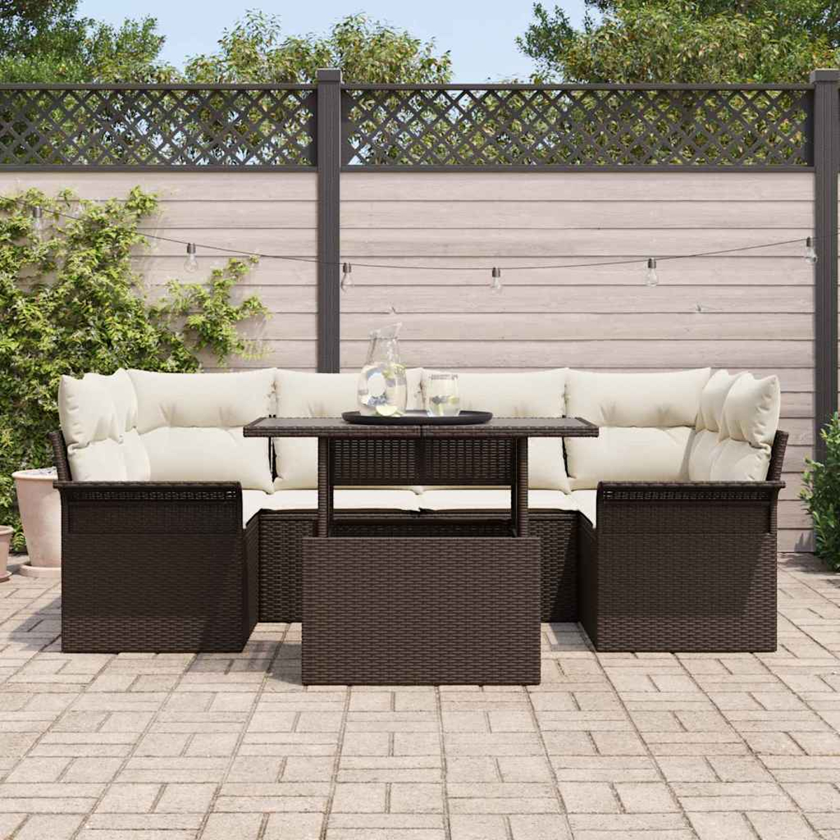 Garten-Korbmöbel-Set mit cremefarbenen Kissen und einem Tisch, Getränke oben. Hintergrund hat einen Zaun und Grün.