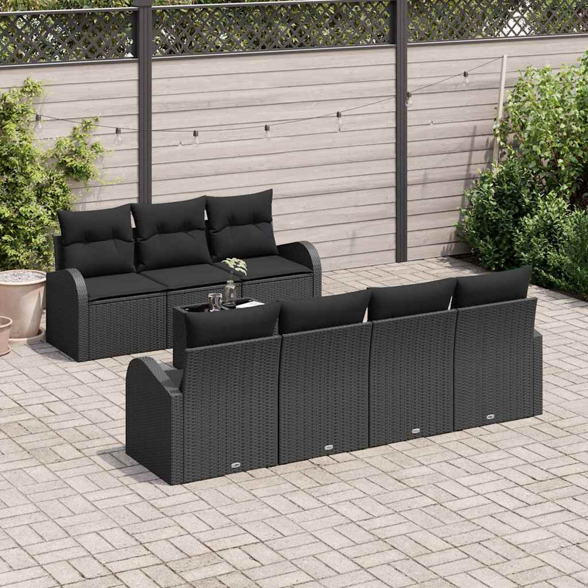 Außenszene mit schwarzen Korbmöbeln. Enthält ein Dreisitzer-Sofa und ein Viersitzer-Sofa. Zwischen ihnen steht ein kleiner Tisch mit Getränken.