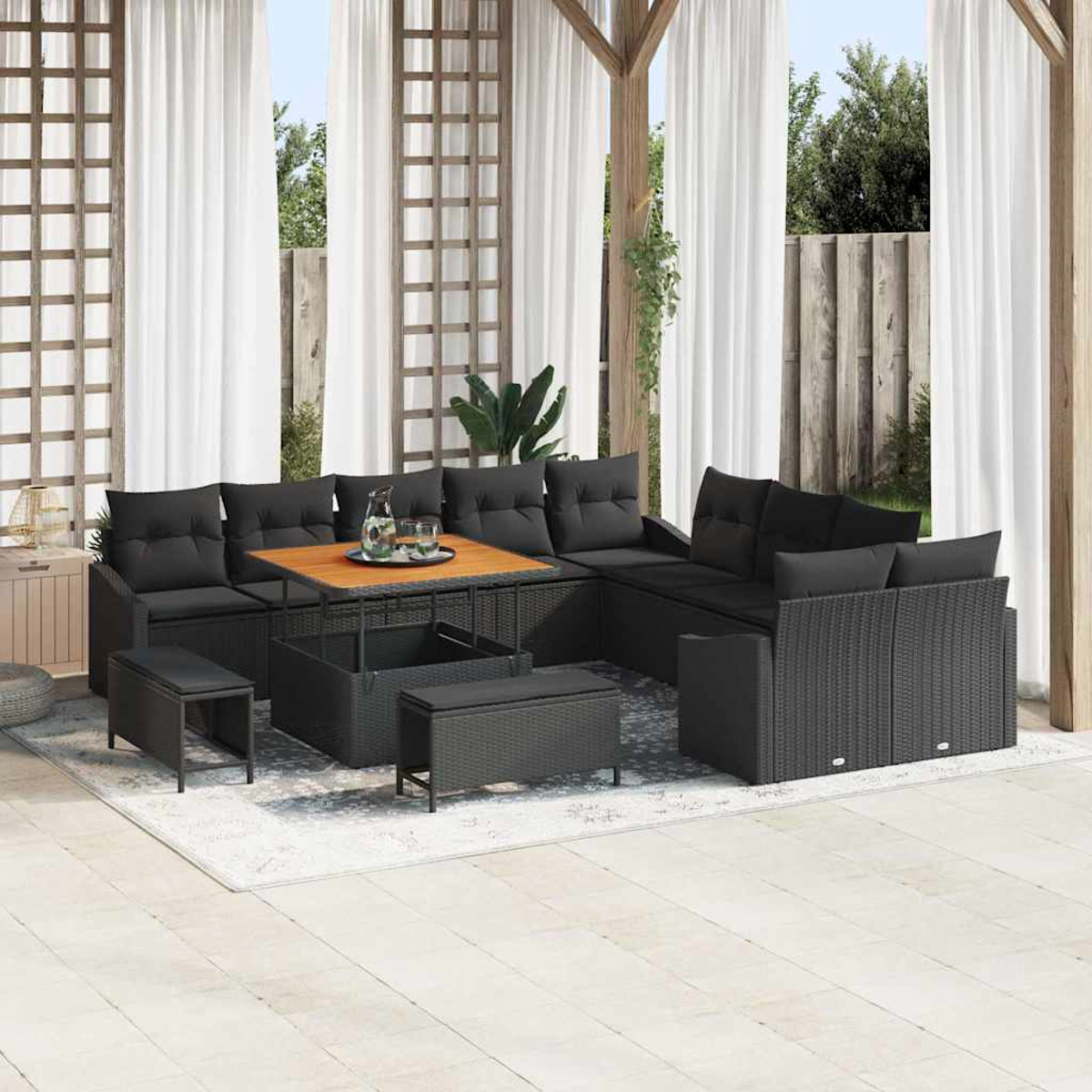 Terrassenset mit schwarzen Kissen und Holztisch. Inklusive Sitzgelegenheiten, kleinen Bänken und einem Teppich auf der Terrasse.