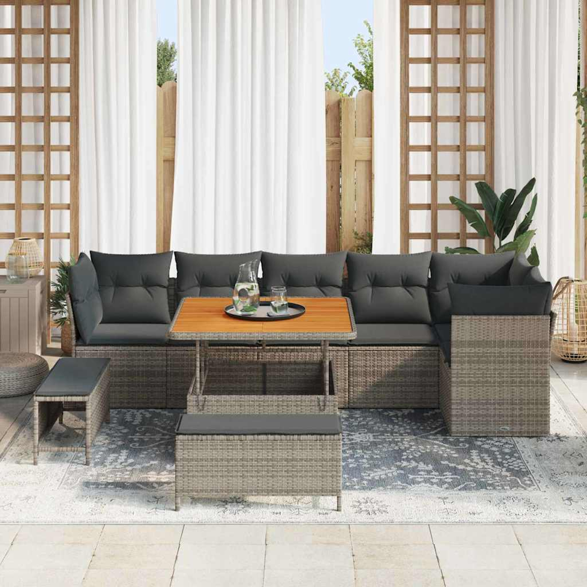 Terrassen-Set mit grauen Kissen, Holztisch und Bank. Weiße Vorhänge im Hintergrund. Auf dem Boden liegt ein Teppich.
