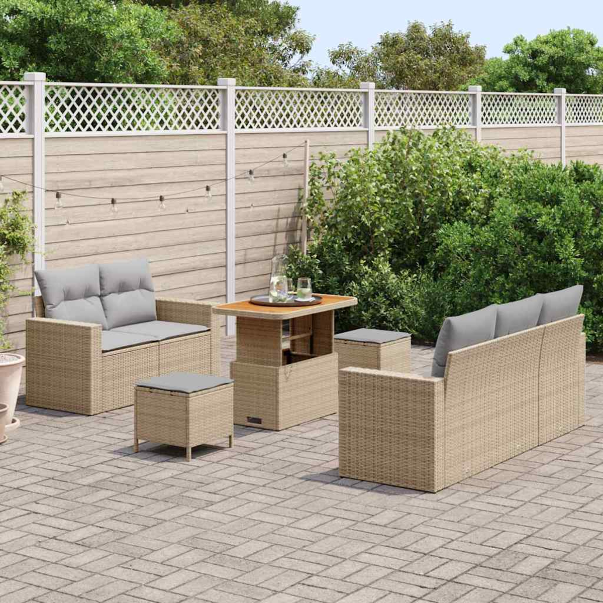 Set patio esterno: divano, divanetto, due pouf e un tavolo. Cuscini grigi. Mobili beige intrecciati. Patio in mattoni con recinzione in legno.