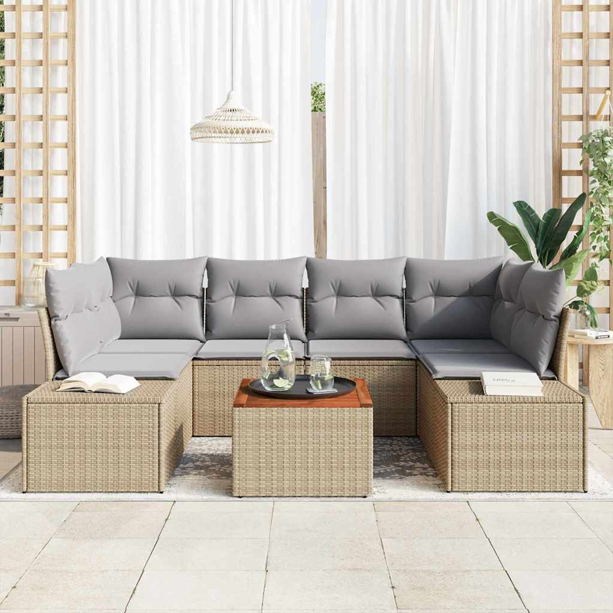 Outdoor-Sitzgruppe mit grauen Kissen, Untergestell im Korbstil, einem Holztisch und weißen Vorhängen im Hintergrund.