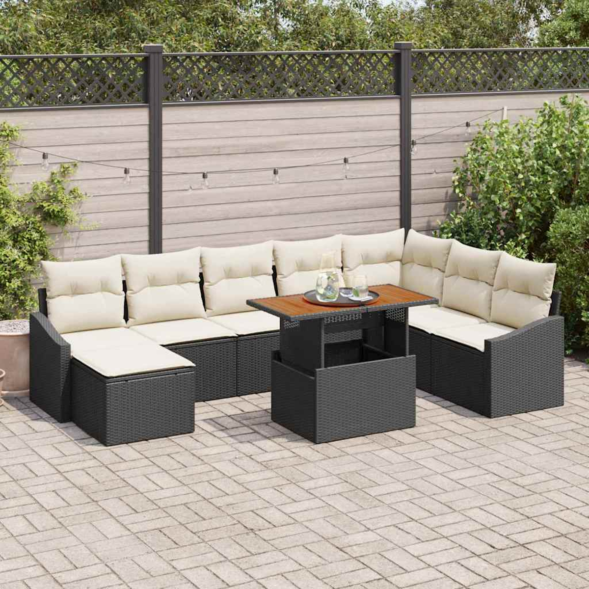 Outdoor-Terrassenset mit beigen Kissen, dunkelgrauem Korbgeflecht und einem Hebetisch. Auf einer Steinterrasse mit Holzzaun.