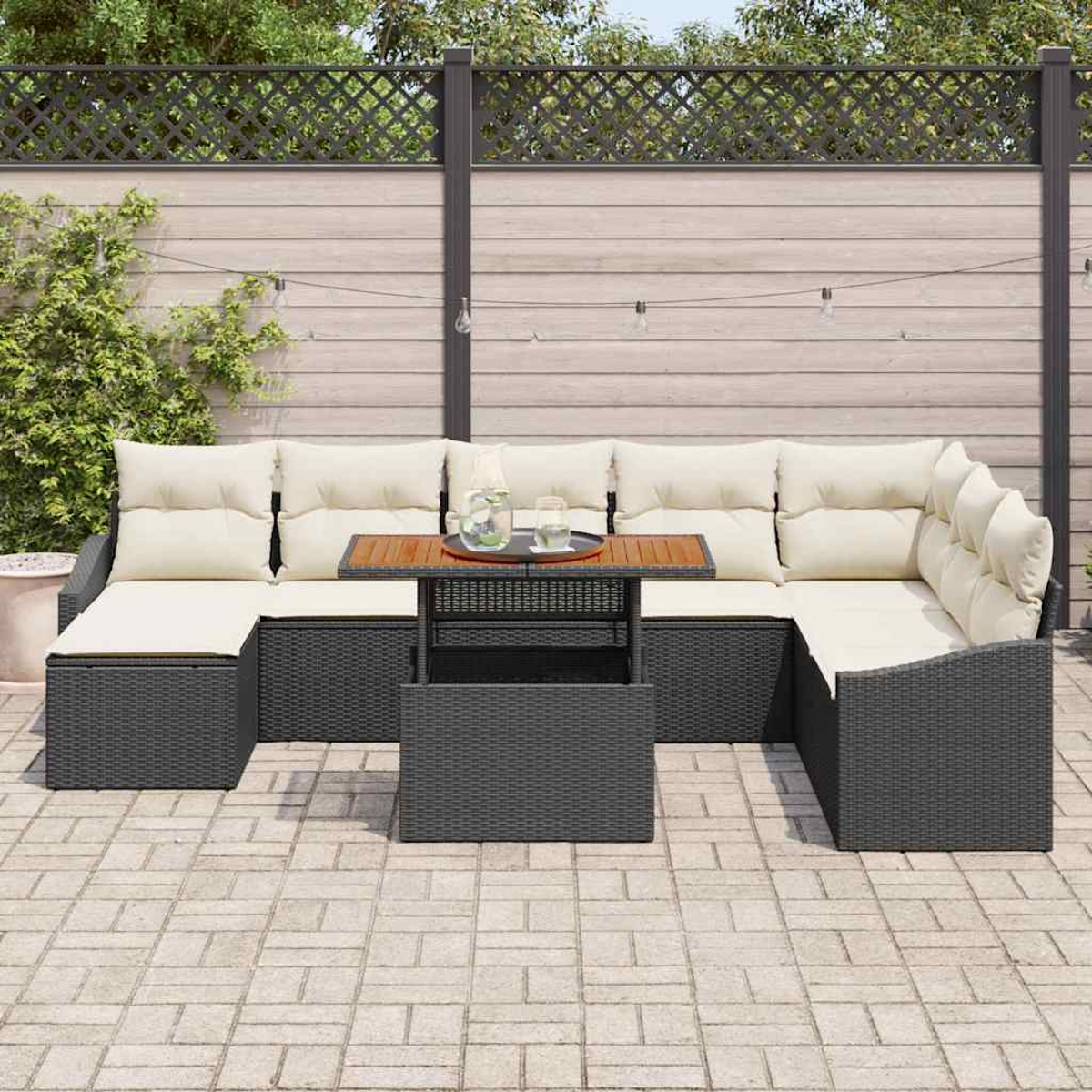 Graues Outdoor-Ecksofa mit cremefarbenen Kissen und einem passenden Couchtisch. Im Hintergrund ein Holzzaun und Grün.