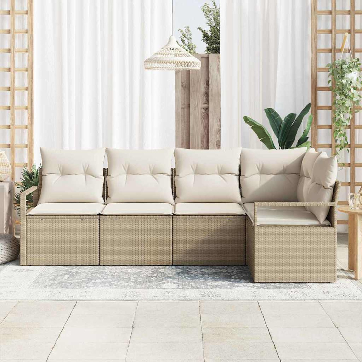 Geflochtenes Outdoor-Ecksofa mit cremefarbenen Kissen. Weiße Vorhänge, Hängelampe und Pflanzen im Hintergrund auf einer gefliesten Terrasse.