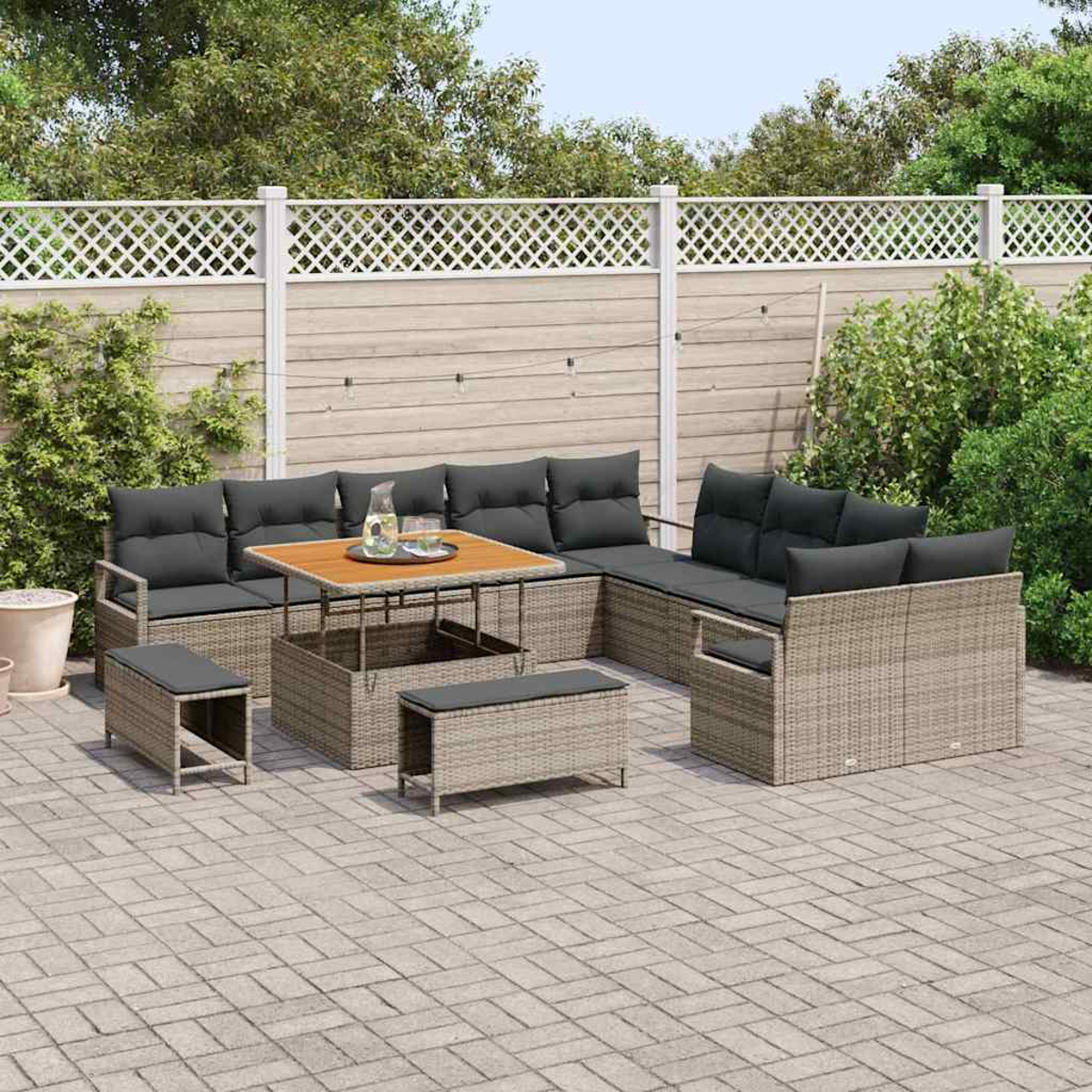 Set di mobili da esterno in vimini con cuscini grigi e tavolo in legno su un patio. Una recinzione bianca e piante verdi sullo sfondo.
