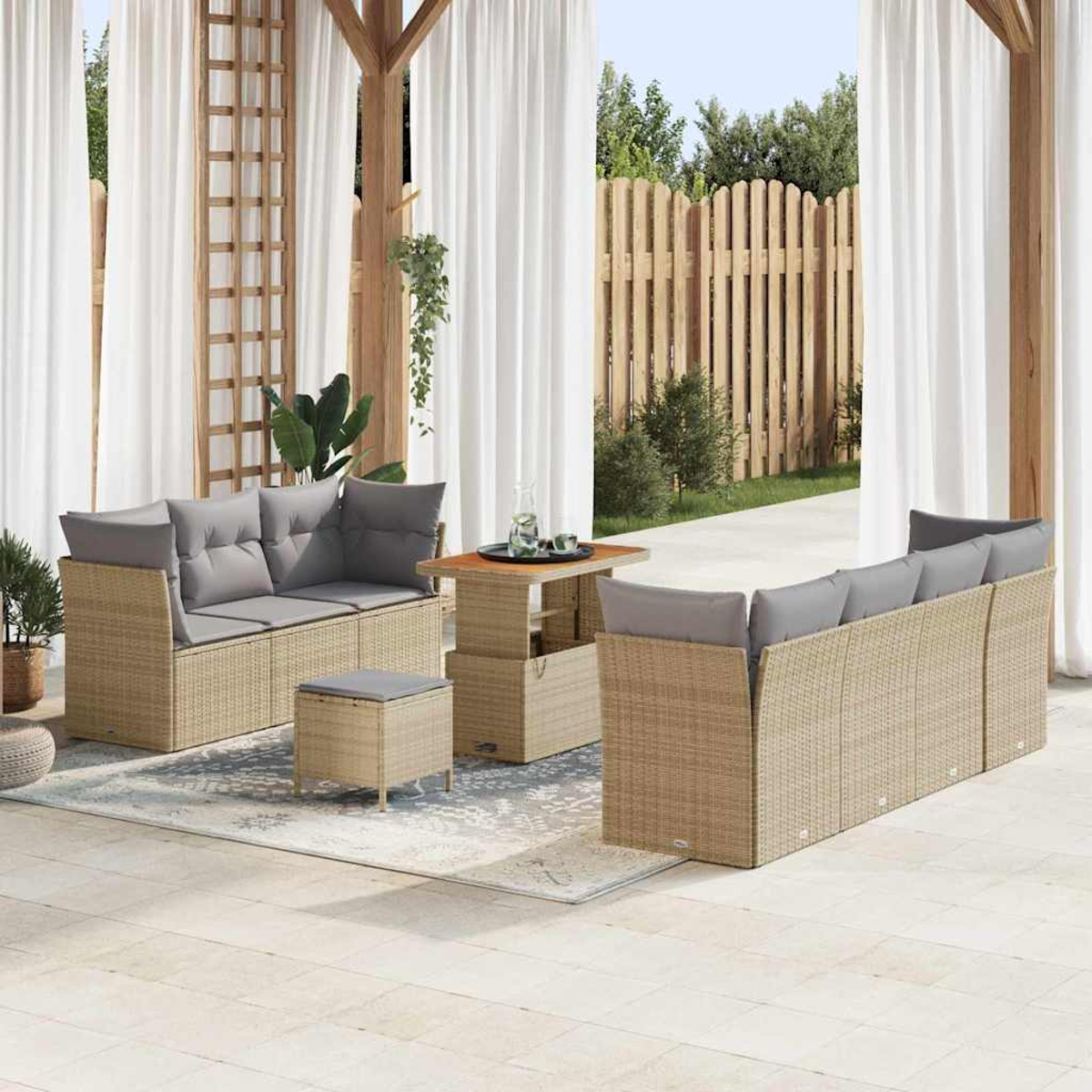 Garten-Sitzgruppe mit beigen Korbmöbeln, grauen Kissen und einem Tisch auf einer Terrasse mit Vorhängen und Holzzaun im Hintergrund.