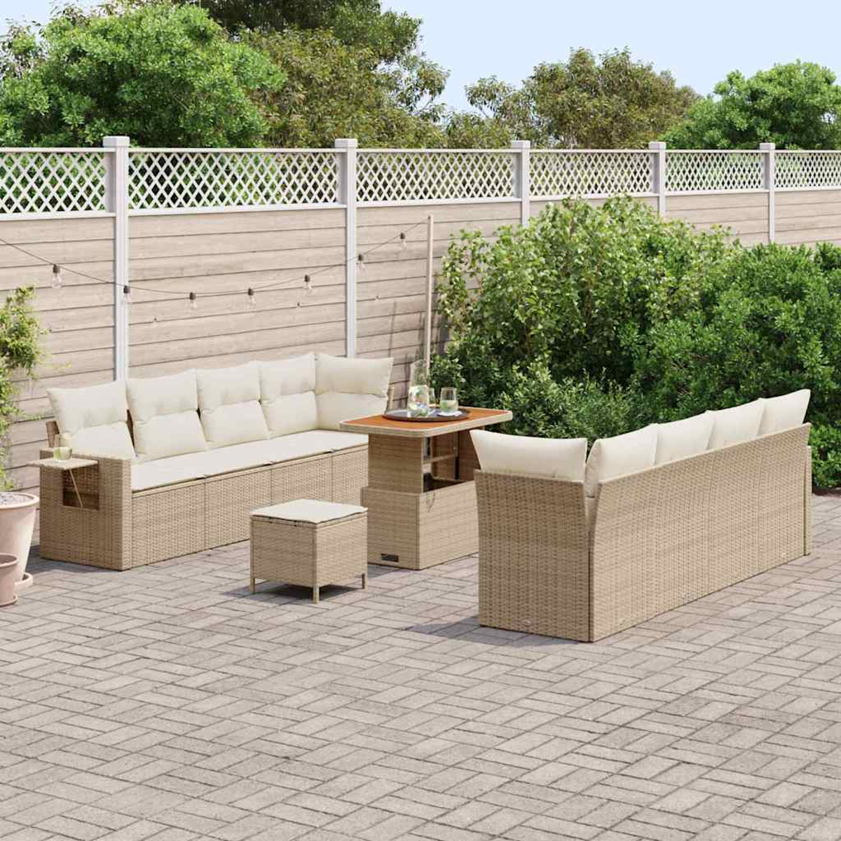 Set da patio esterno con cuscini beige, su un patio in mattoni. Include divano, tavolo, pouf e vegetazione sullo sfondo.