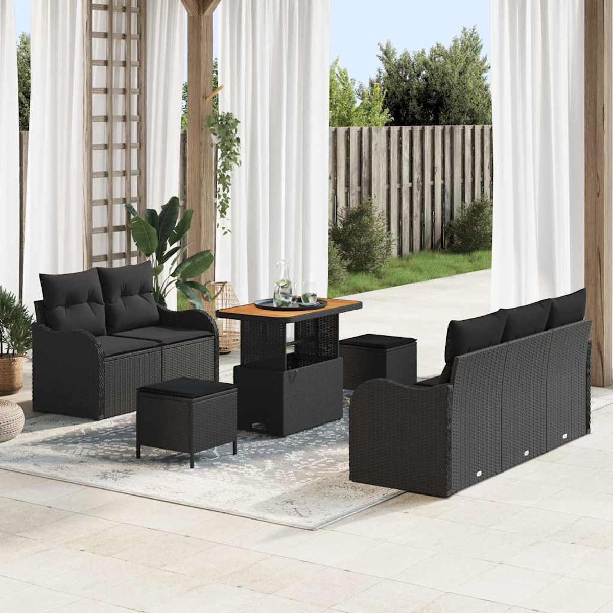 Terrassenmöbel-Set mit schwarzem Korbmöbel, Sofa, zwei Stühlen, Ottomanen und Tisch auf einem Teppich in der Nähe von Vorhängen.