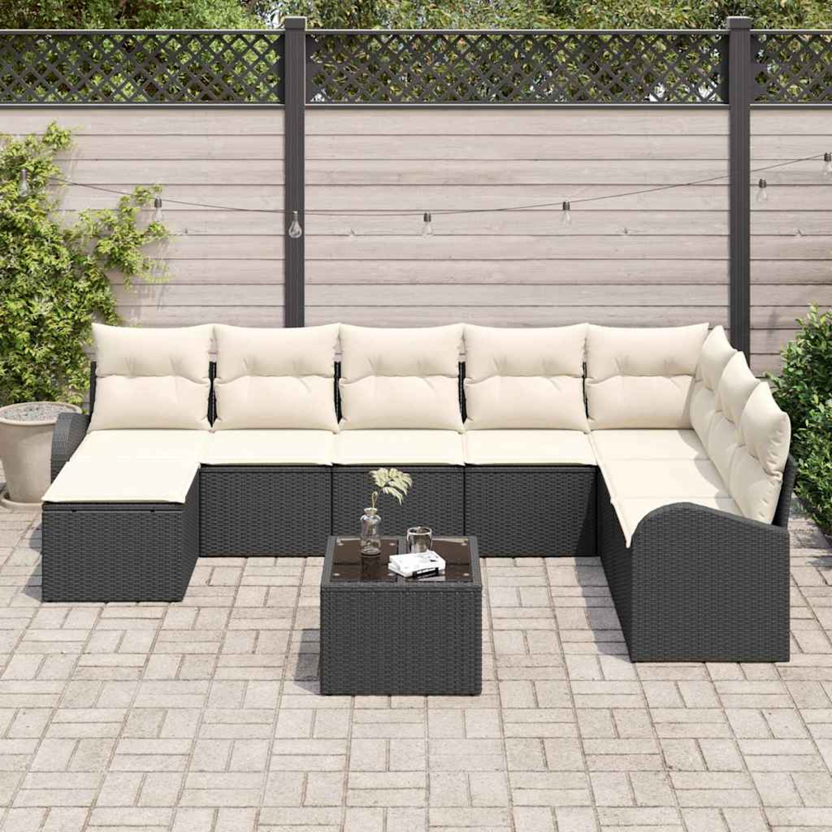 Outdoor-Ecksofa mit cremefarbenen Kissen und einem quadratischen Couchtisch. Im Hintergrund ist ein Zaun.
