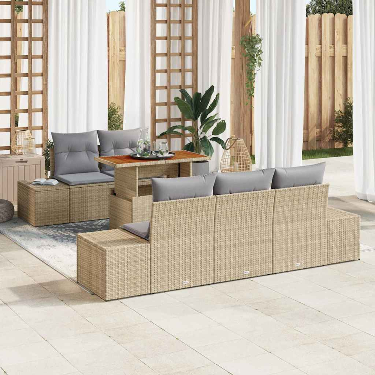 Gartenmöbel-Set aus Korbgeflecht mit grauen Kissen auf einer gefliesten Terrasse in der Nähe eines Holzzauns.