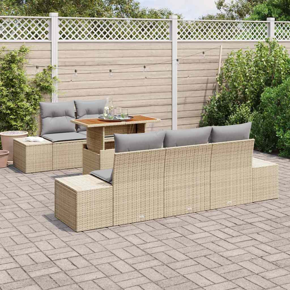 Garten-Terrassenset mit beigefarbenen Webmöbeln, grauen Kissen und einem Holztisch. Der Hintergrund umfasst einen Zaun und Grün.