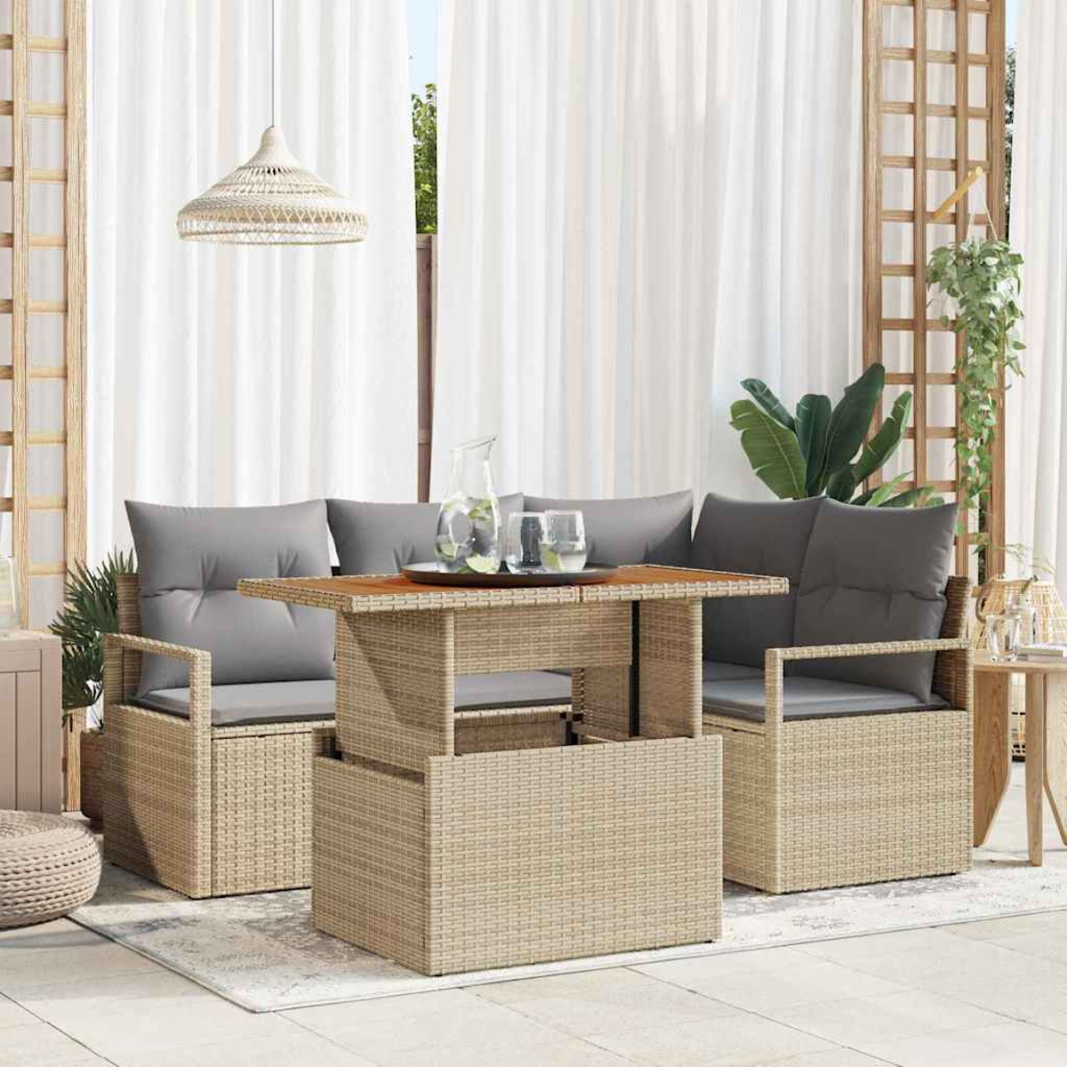 Gartenmöbel-Set aus Korbgeflecht mit grauen Kissen und einem Holztisch. Weiße Vorhänge und eine Hängelampe im Hintergrund.