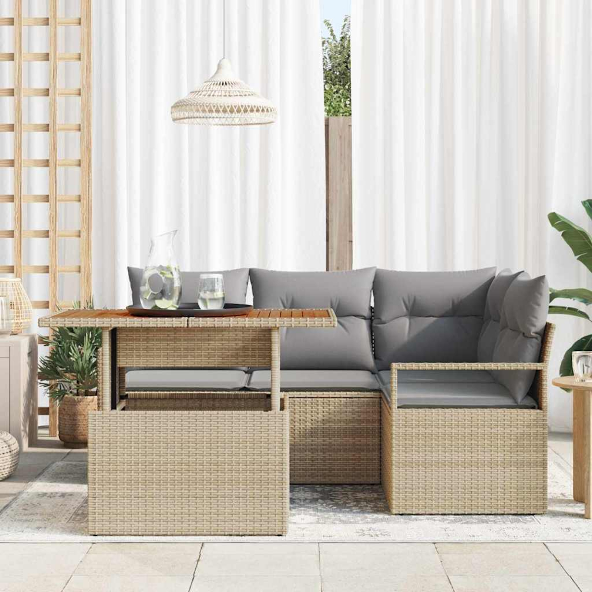 Sitzbereich im Freien mit Rattanmöbeln, grauen Kissen, einem Tisch mit einem Wasserkrug und weißen Vorhängen.