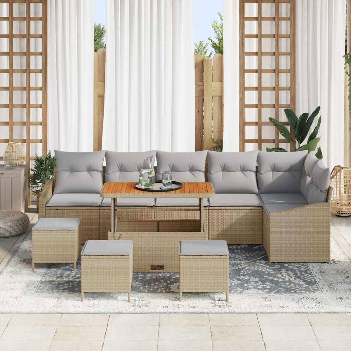 Outdoor-Wicker-Sofa mit grauen Kissen, Holztisch und vier Hockern. Weiße Vorhänge und Holzgitter im Hintergrund.