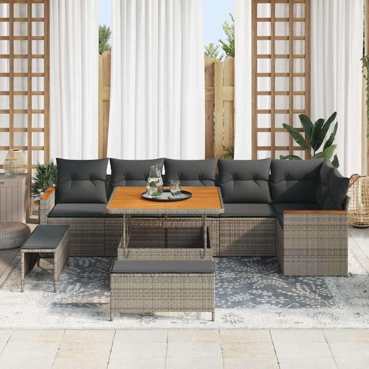 Garten-Set mit grauen Kissen. Es umfasst einen Tisch, eine Bank und ein Sofa. Im Hintergrund ein Zaun, weiße Vorhänge und Pflanzen.