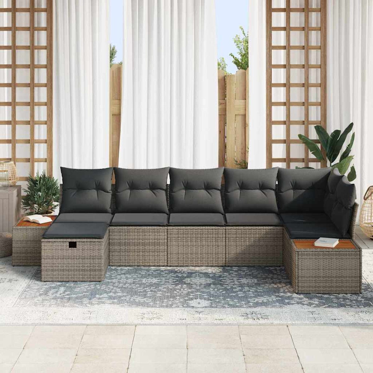 Outdoor-Ecksofa mit grauen Kissen. Gewebte Basis, hölzerne Beistelltische. Weiße Vorhänge und Holzgitter im Hintergrund.