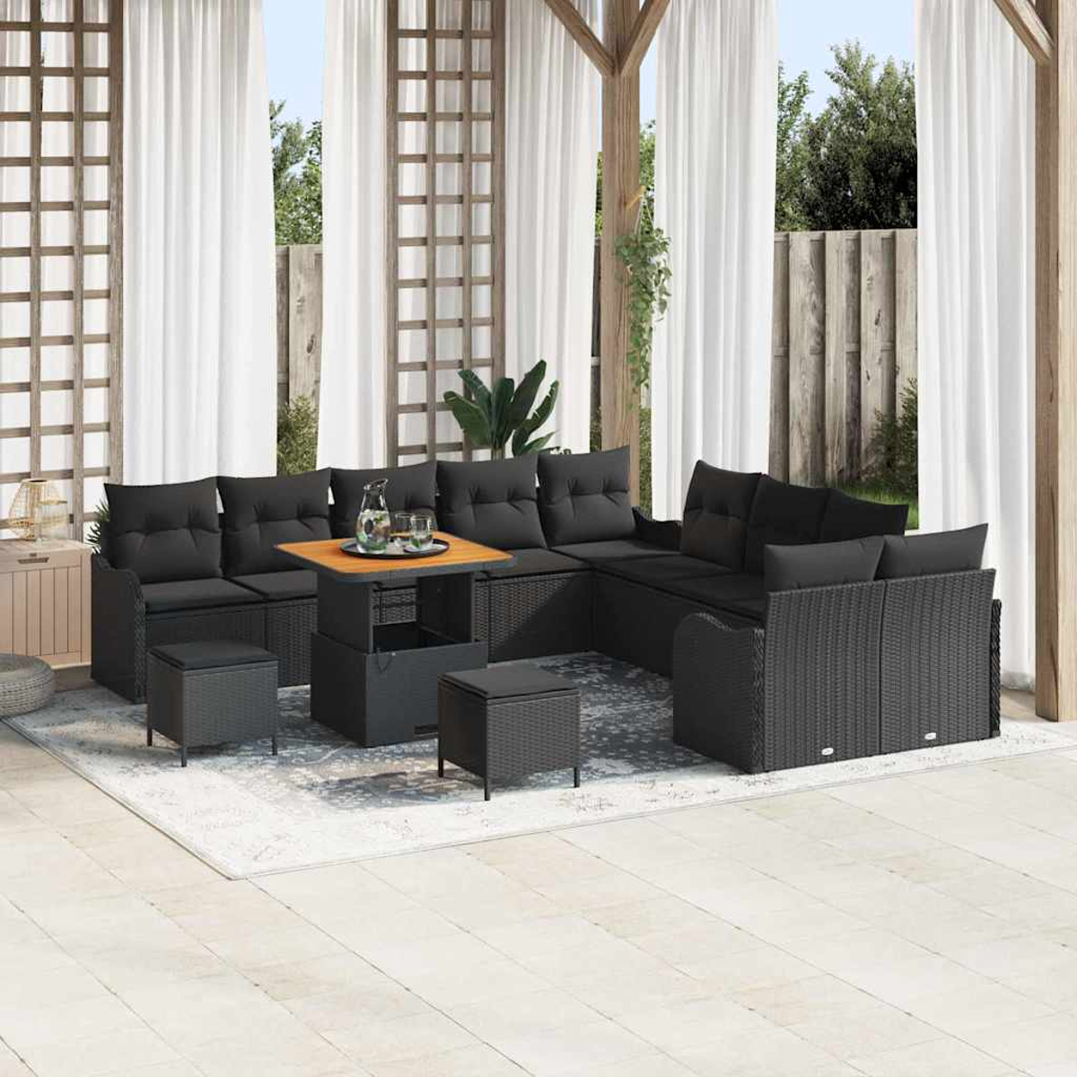 Garten-Sitzgruppe mit schwarzen Kissen und Tisch. Weiße Vorhänge im Hintergrund, die einen entspannten Außenbereich schaffen.