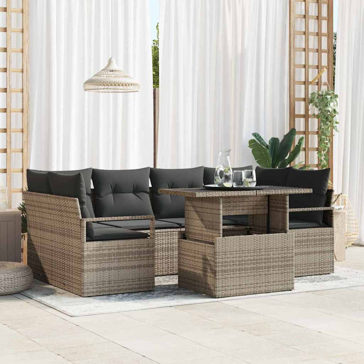 Gartenmöbel-Set aus Korbgeflecht mit grauen Kissen. Enthält einen Tisch, zwei Sessel und ein Sofa, mit weißen Vorhängen im Hintergrund.