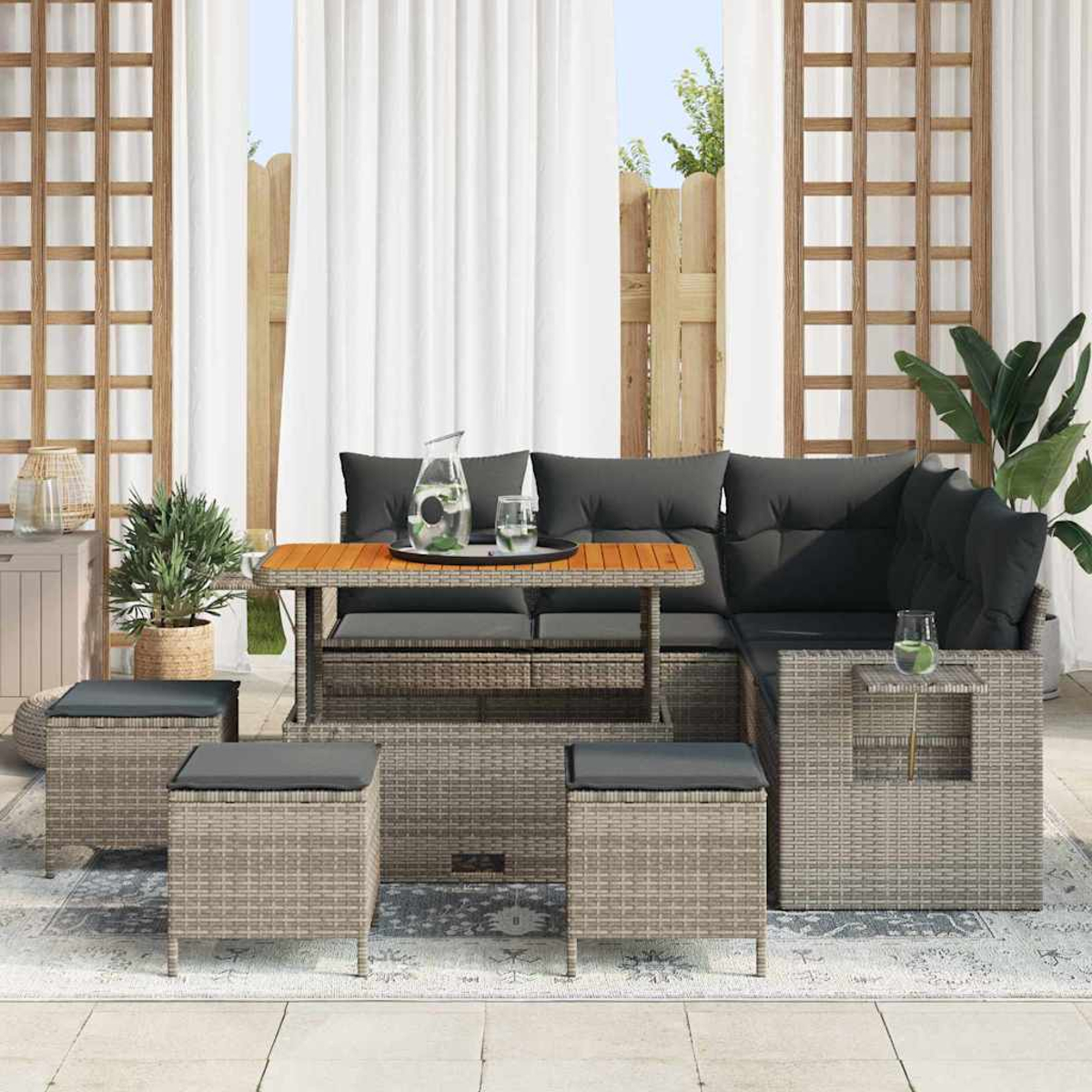 Garten-Set mit grauen Kissen, Holztisch und drei Hockern. Weiße Vorhänge und eine Pflanze im Hintergrund.