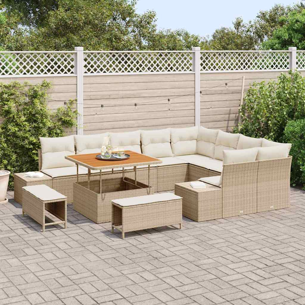 Beige Rattan-Outdoor-Ecksofa mit Couchtisch, Ottomanen und einem dekorativen Zaun im Hintergrund. Gepflasterte Terrasse.
