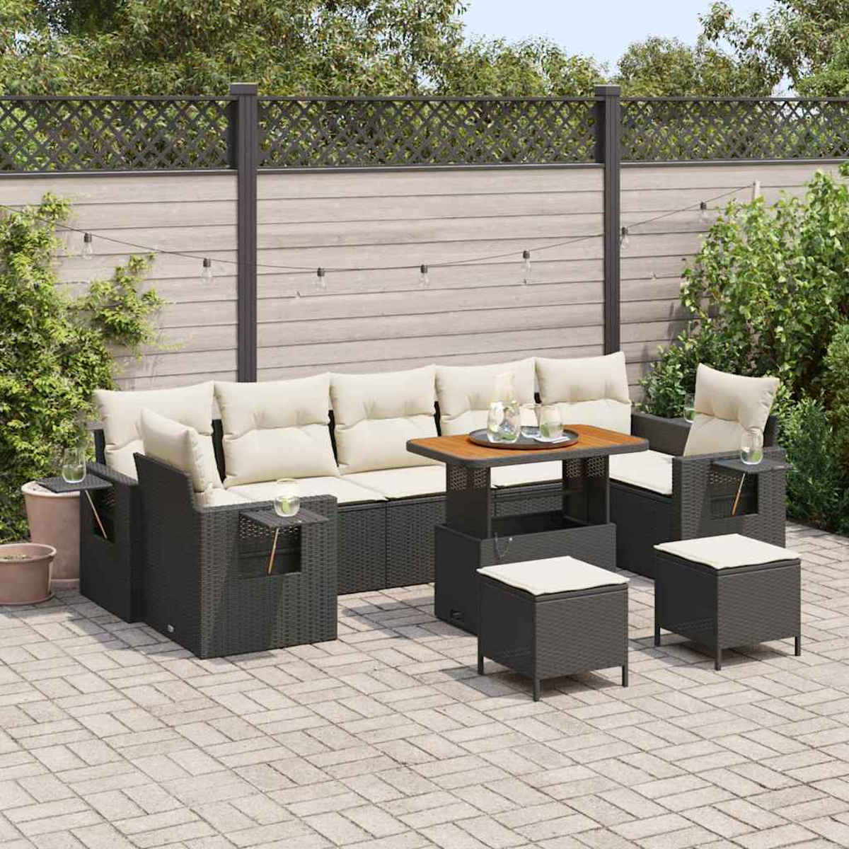 Outdoor-Terrassenset mit schwarzem Korbsessel, zwei Sesseln, einem Tisch und zwei Hockern. Beige Kissen, Holztisch und Lichterketten.