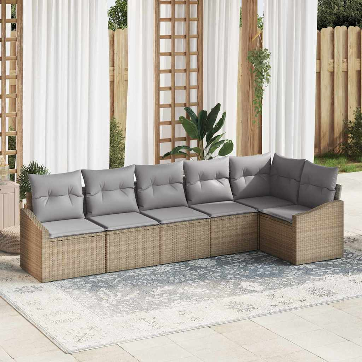 Ein Ecksofa im Freien mit grauen Kissen auf einem gemusterten Teppich, Vorhängen und einem Holzzaun im Hintergrund.