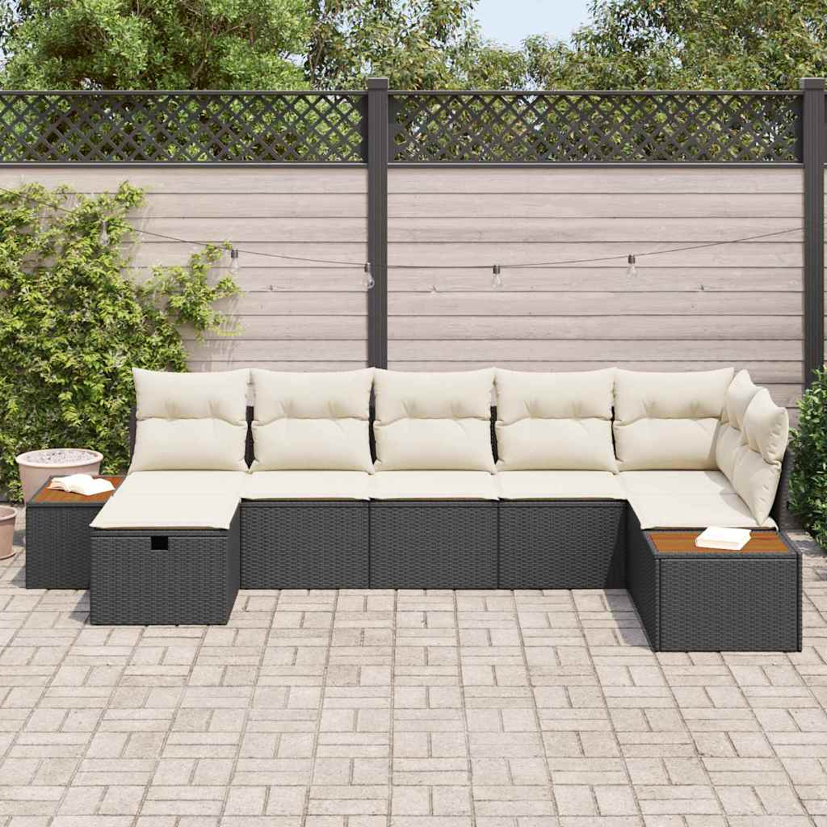 Ein Ecksofa für den Außenbereich mit beigen Kissen steht auf einer Terrasse. Im Hintergrund befindet sich ein Holzzaun mit Pflanzen.