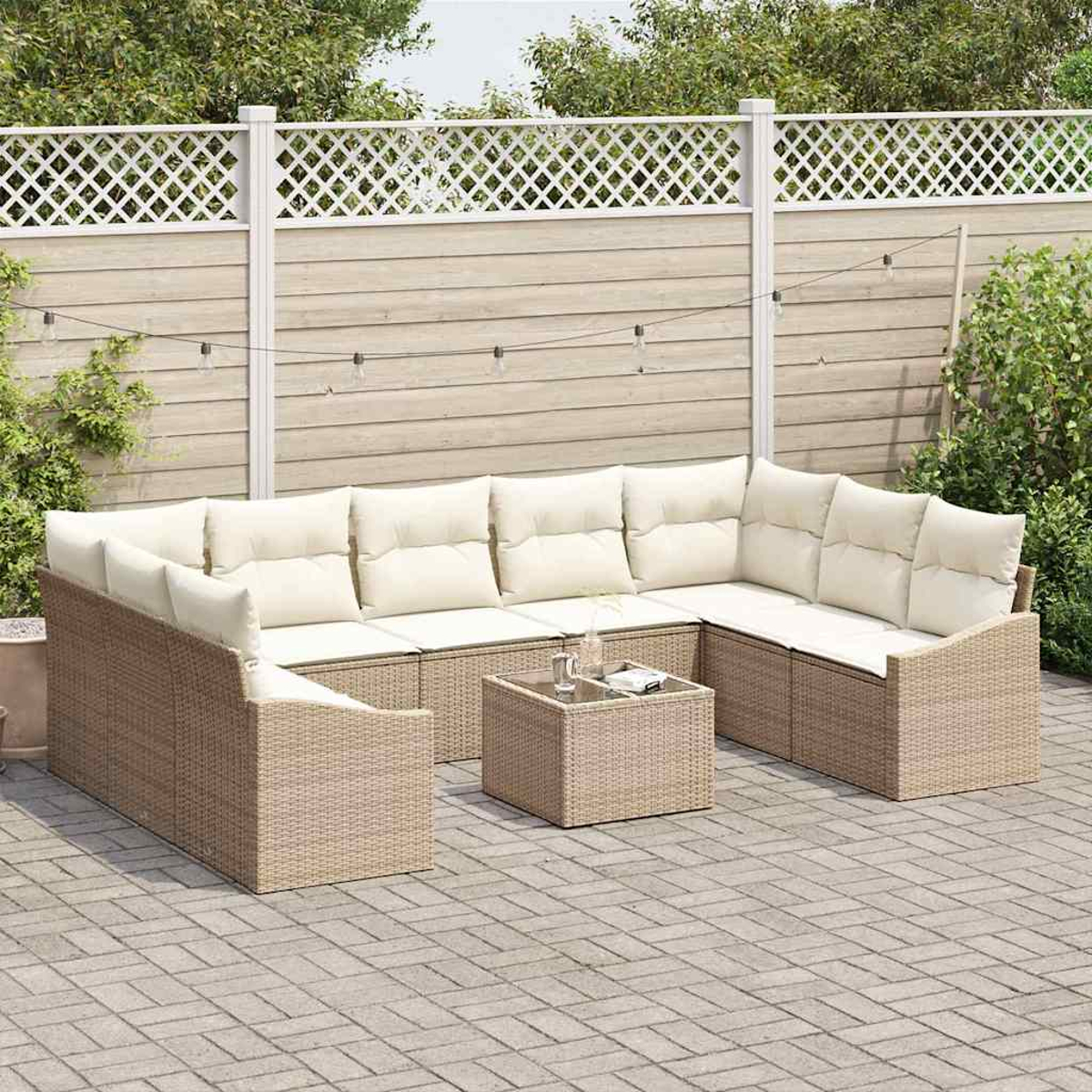 Ein beiges Korbsessel-Ecksofa mit cremefarbenen Kissen steht auf einer Ziegelterrasse. Davor steht ein kleiner quadratischer Tisch. Dahinter befindet sich ein weißer Gitterzaun.