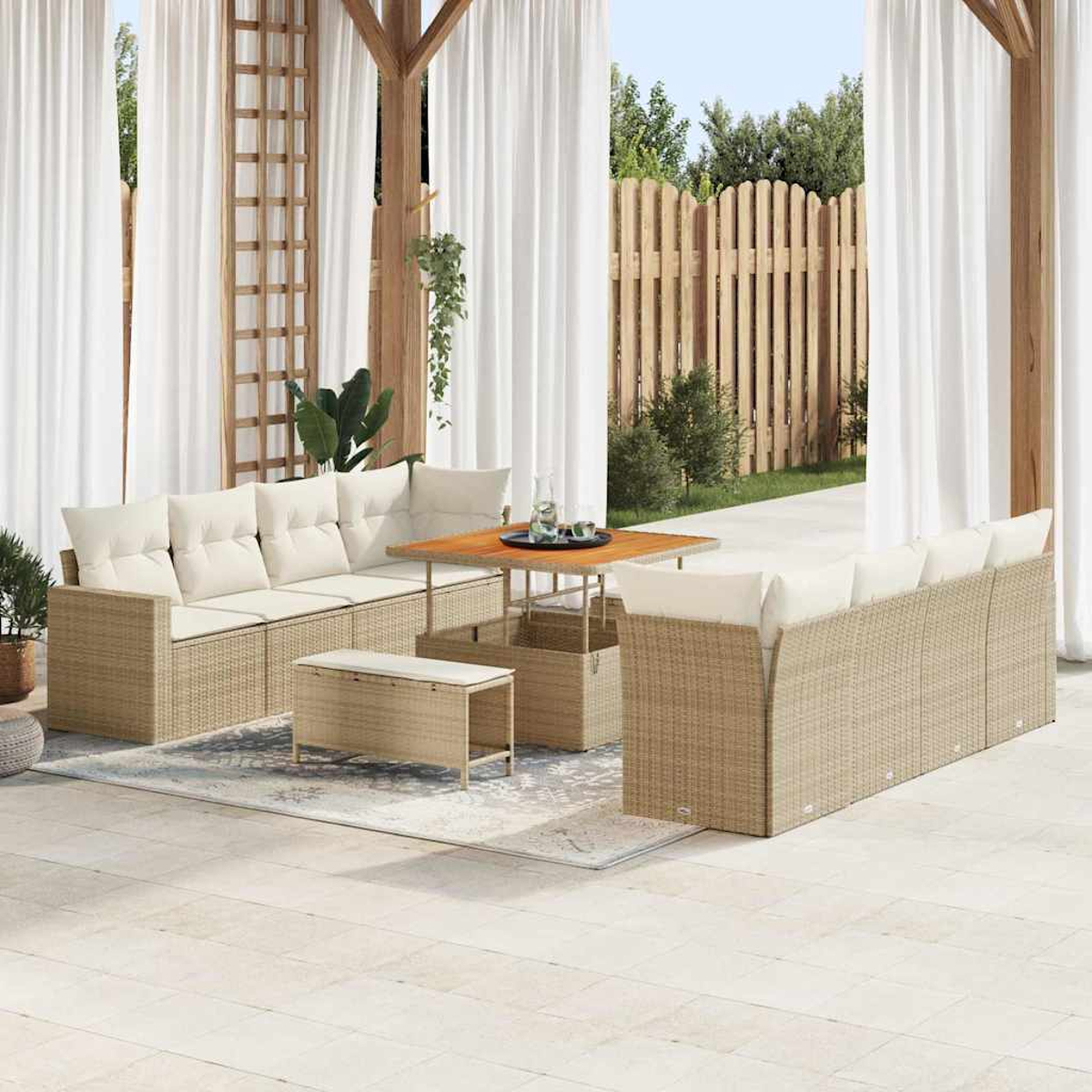 Ein Outdoor-Terrassenset mit beigen gewebten Möbeln und weißen Kissen. Ein Holztisch, Vorhänge und ein Zaun befinden sich im Hintergrund.