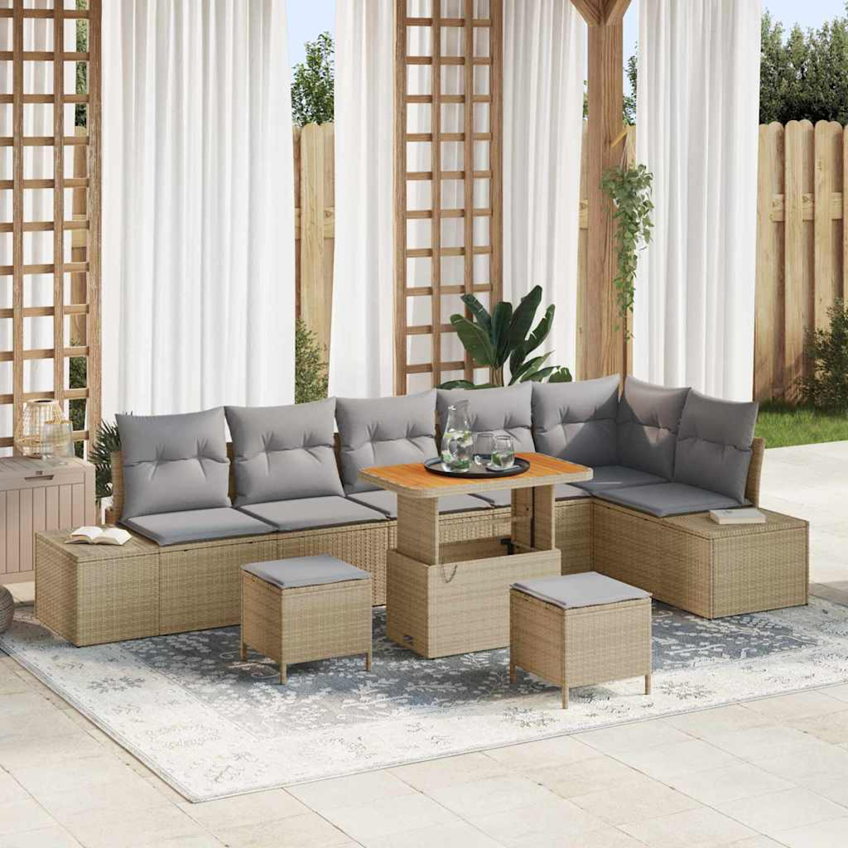 Gartenlounge mit grauen Kissen, einem Holztisch und Hockern auf einem gemusterten Teppich. Weiße Vorhänge im Hintergrund.