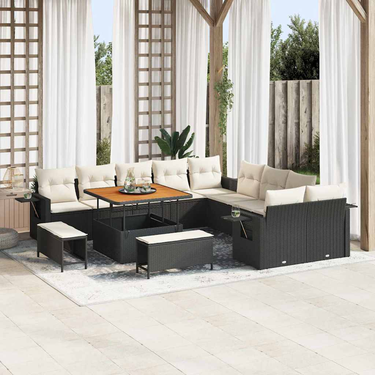 Terrassenmöbel-Set mit schwarzem Korbmöbeln und beigen Kissen. Ein Holztisch steht in der Mitte, und weiße Vorhänge sind im Hintergrund.