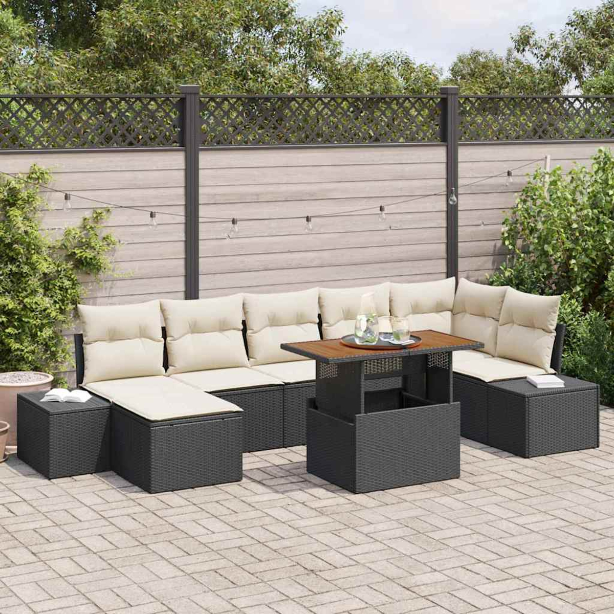 Gartenmöbel-Set. Dunkelgraue Korbsessel mit beigefarbenen Kissen. Holztisch und Beistelltisch. Hintergrund ist ein Holzzaun.