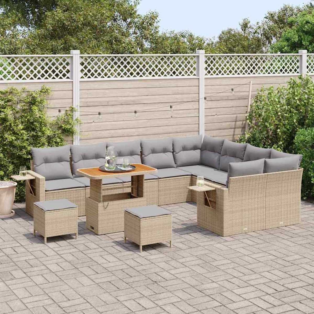 Outdoor-Ecksofa mit grauen Kissen und Tisch. Zwei Ottomane. Auf einer Ziegelterrasse mit weißem Zaun im Hintergrund.