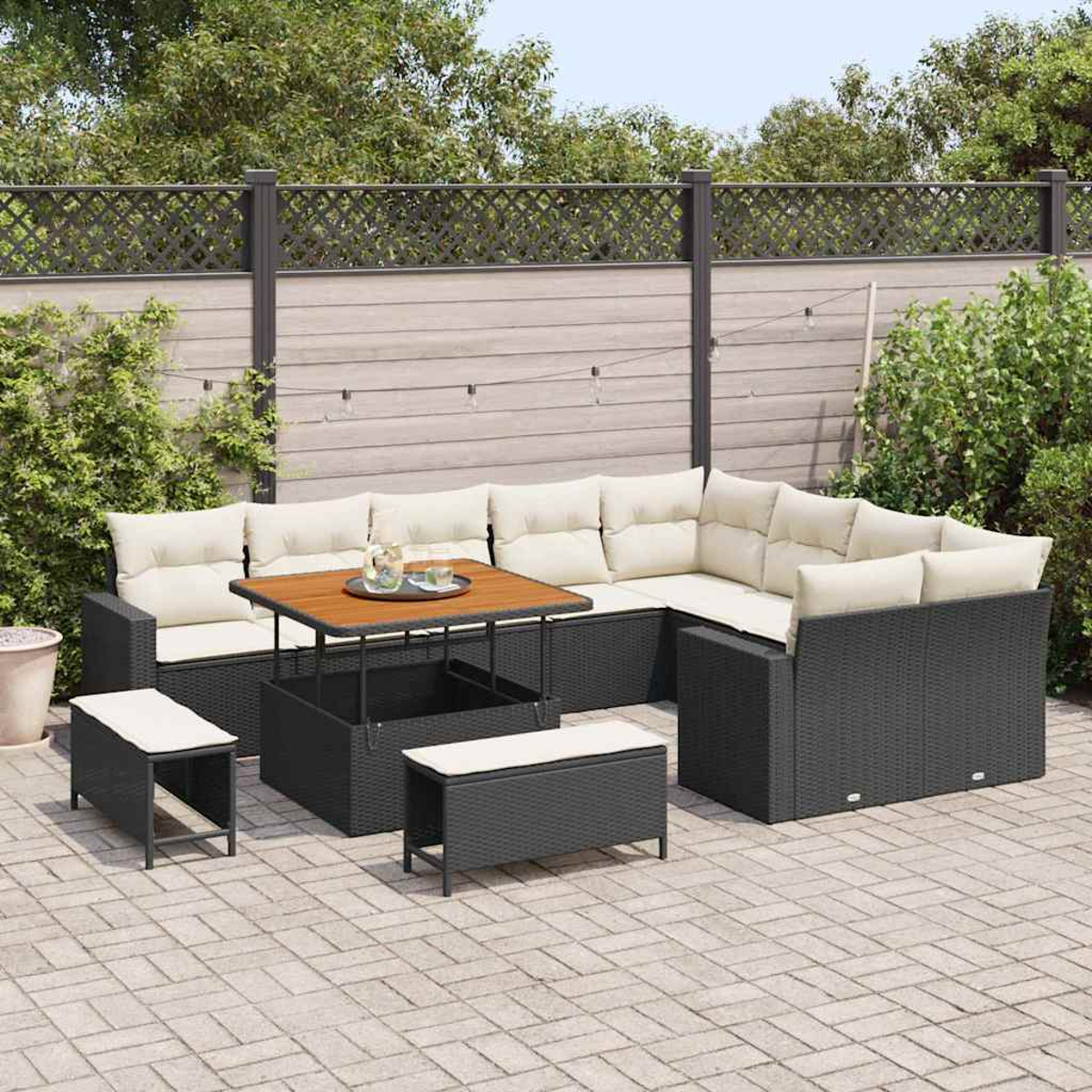Outdoor-Sofa-Set mit Hebetisch und Bänken. Merkmale: schwarze Korbmöbel, cremefarbene Kissen, auf einer Terrasse.