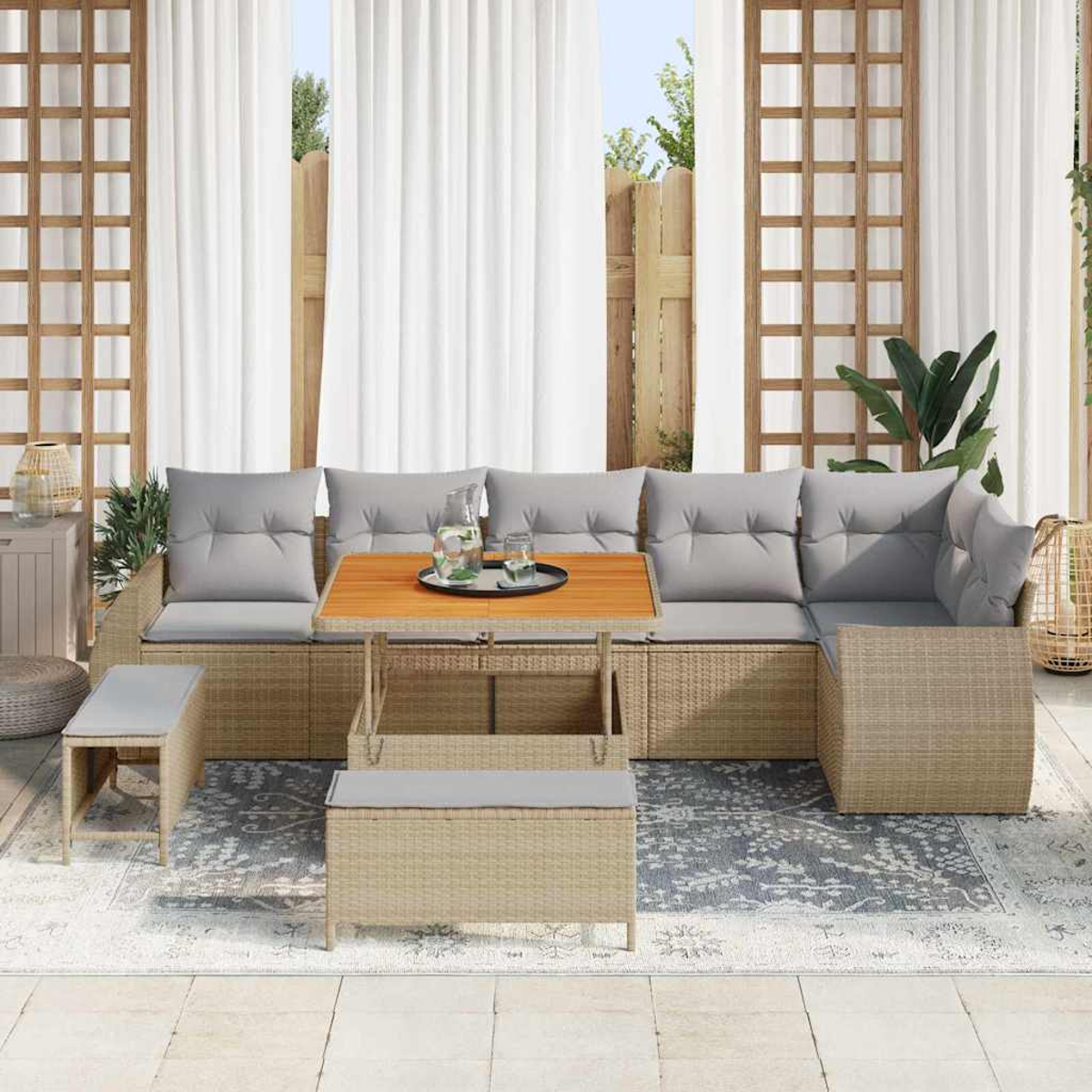 Gartensitzgruppe mit Tisch, Kissen und Bank. Im Hintergrund weiße Vorhänge und Holzgitter. Auf dem Boden liegt ein Teppich.