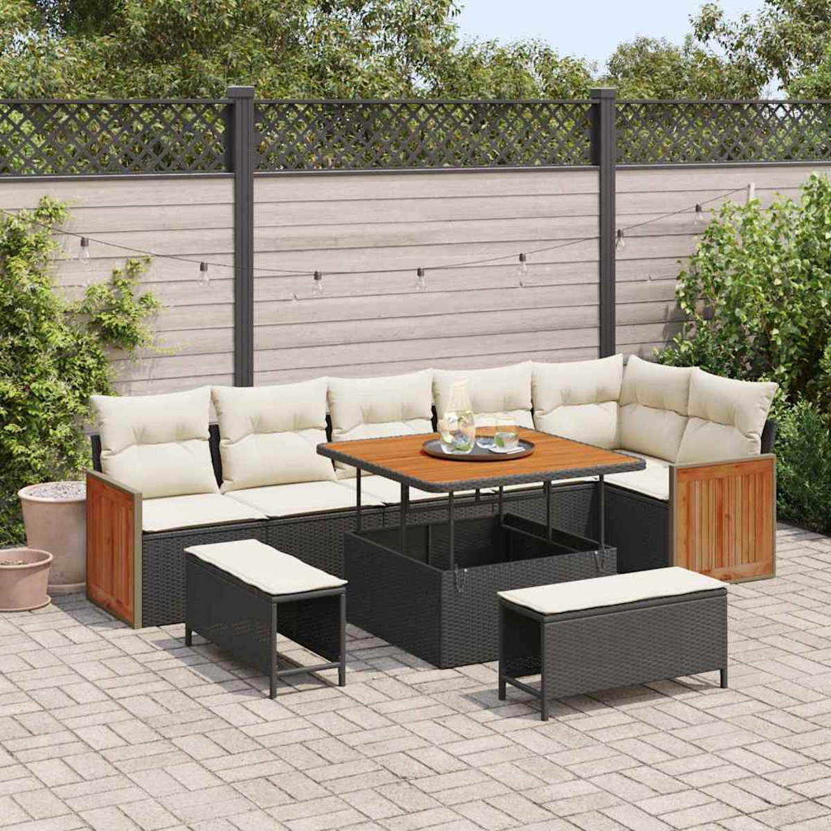 Terrassenset mit Sofa, Bänken und Tisch mit Getränken. Beige Kissen, Holzakzente und grauer Zaun im Hintergrund.