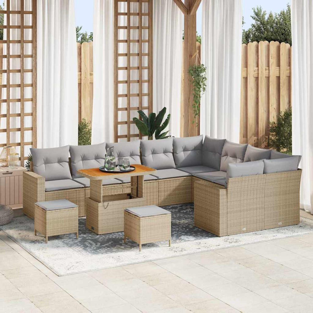 Outdoor-Ecksofa mit grauen Kissen, einem Holztisch und zwei kleinen Hockern auf einem Teppich. Transparente Vorhänge im Hintergrund.