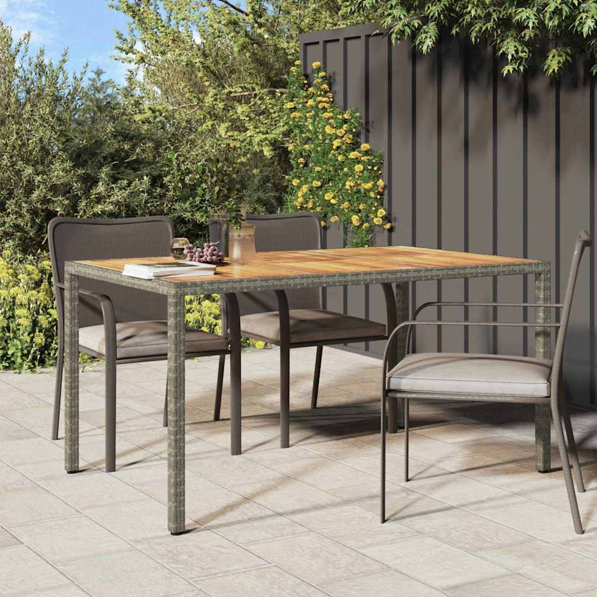 Essgarnitur im Freien: Tisch mit Stühlen. Der Tisch hat eine Holzplatte mit Metallrahmen. Stühle stehen um den Tisch. Grünzeug im Hintergrund.